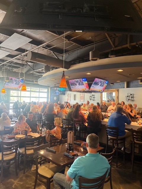 Lively crowd seated at the bar with TVs overhead