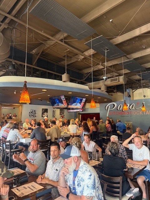 Packed dining room at Papa's Kitchen + Cocktails with the signature wall logo