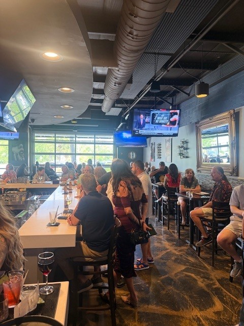 Patrons mingling near the bar and large windows