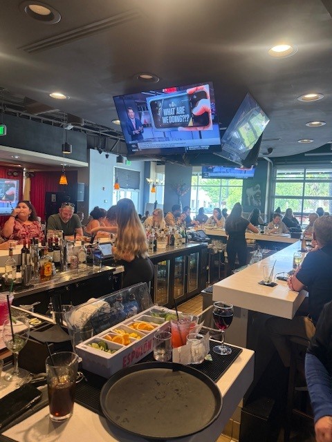 Bar top with fresh cocktail garnishes and the game on the TV